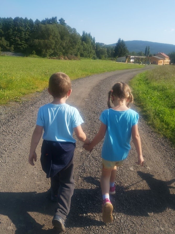 děti držící se za ruce kráčející po cestě